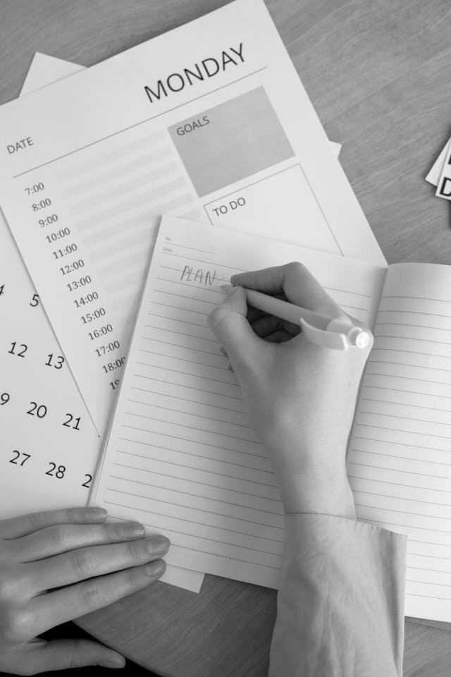 Woman tracking 30-day smoke-free progress with marked calendar - quit smoking plan Hand with pen resting on an open calendar showing "plan," symbolizing the creation of a 30-day strategy on how to quit smoking successfully.
