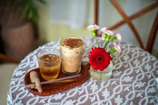 Cup of herbal tea and coffee with milk and cinnamon on a wooden stand