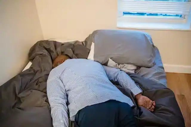 Man sleeping face down on bed symbolizing fatigue and poor sleep quality after night shift