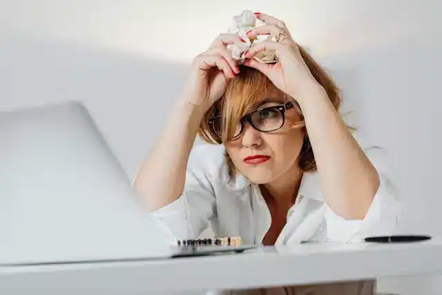 Woman looking fatigued and drained at her desk, illustrating effects of dehydration in Hydration Tracking Systems Review