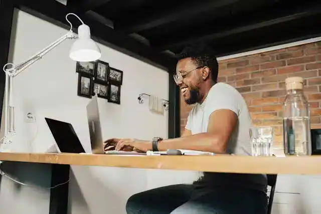 Young male office worker at desk with laptop, papers, water carafe, and glass, illustrating convenient silent hydration reminders from hydration tracking systems.