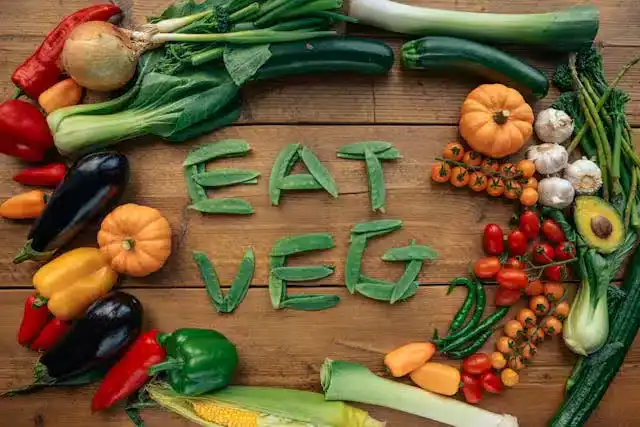 Mediterranean Diet for Gut Health: assorted vegetables arranged in a circle on a wooden table, with “eat veg” spelled out using green beans inside the circle.