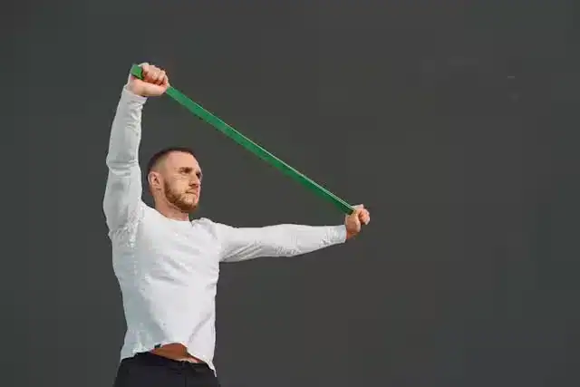 Man performing posture correction resistance band exercises to strengthen shoulder girdle