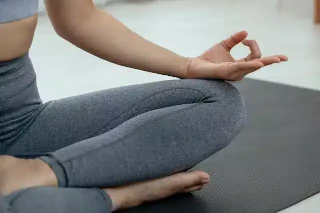 Woman sitting comfortably meditating and doing breathing exercises before sleep, demonstrating calming practices for Sleep Hygiene for Menopause