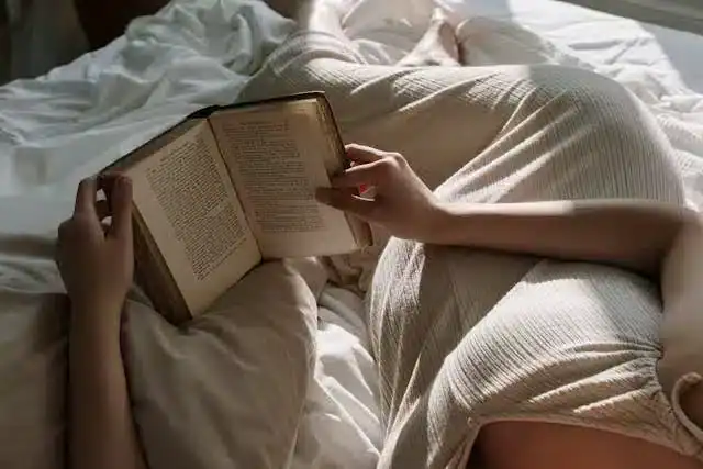Woman preparing for bed by reading a book, illustrating a calming bedtime routine and Sleep Hygiene for Menopause
