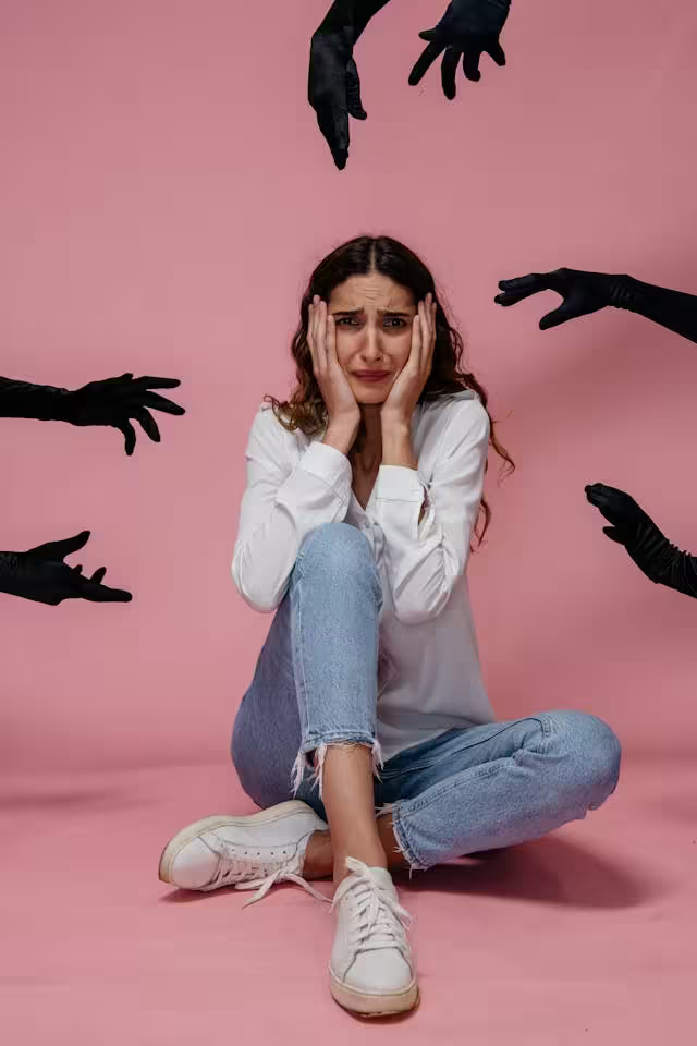 Woman sitting on floor looking distressed, surrounded by symbolic hands representing panic attacks